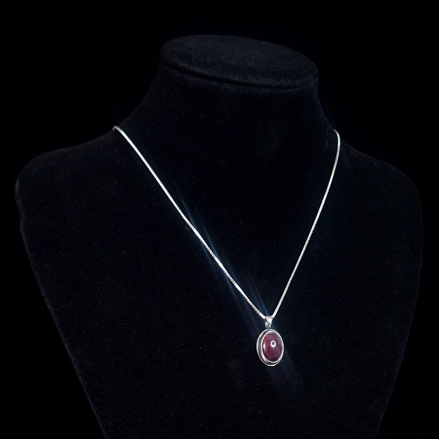 Studio-crafted RBZ Jewelry Gothic Sterling silver pendant featuring a Natural African Ruby cabochon, displayed on a black velvet necklace bust to show how the pendant hangs from its silver chain.