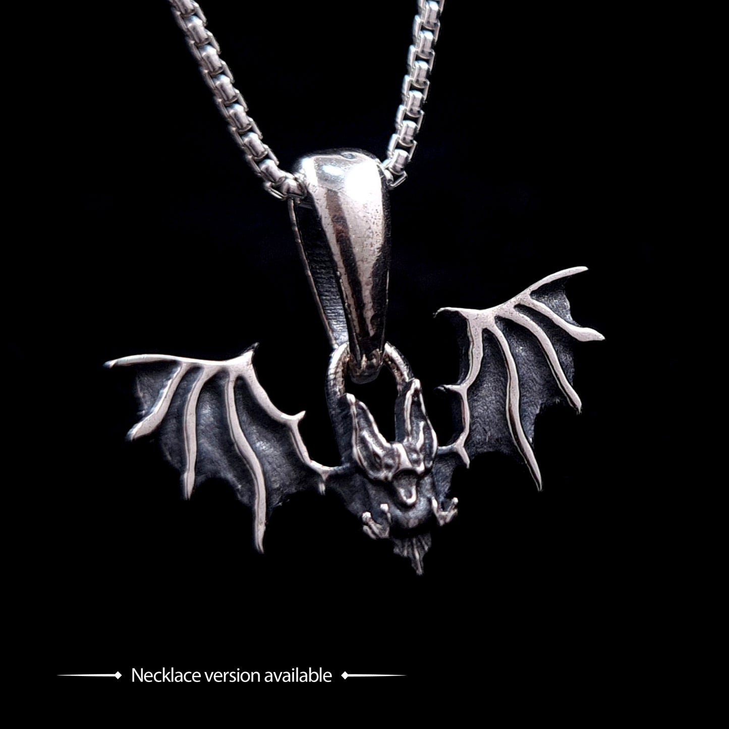 Gothic Sterling silver Glitched Bat pendant necklace by RBZ Jewelry, featuring a visceral, distorted bat silhouette with textured spread wings on a silver box chain. The image includes text at the bottom stating "Necklace version available," set against a solid black background.