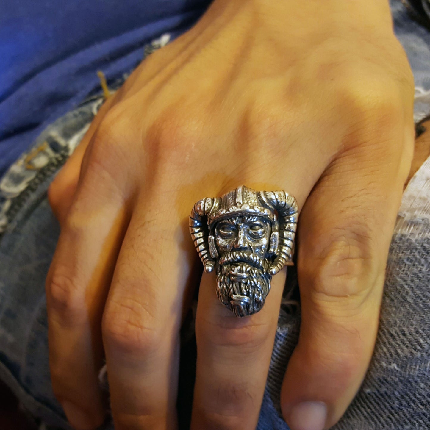 Sterling silver Viking warrior ring by RBZ Jewelry shown on a male hand, highlighting the large, hand-sculpted warrior face and horned helmet in a lifestyle shot against a denim background.