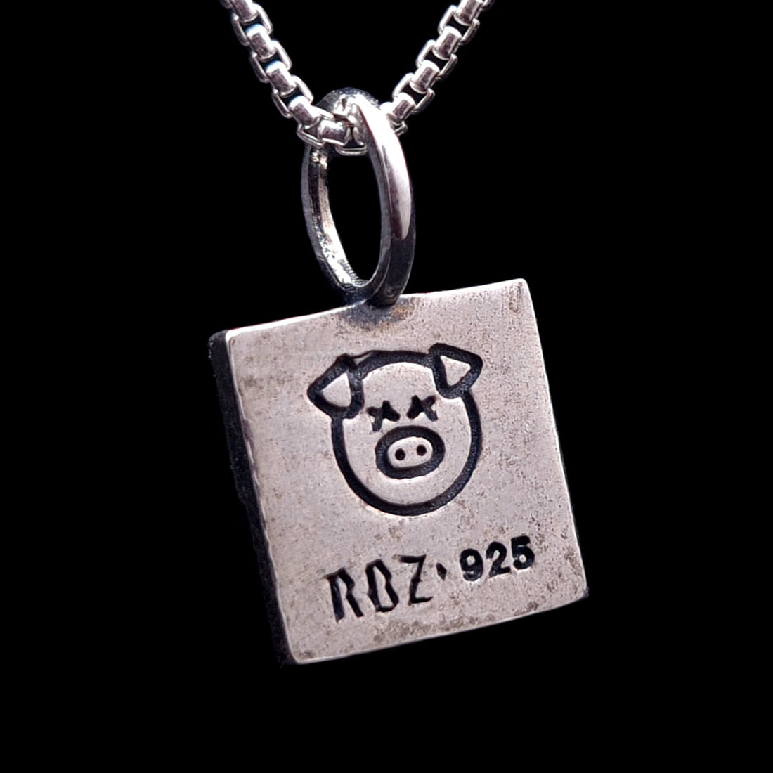 Reverse side of the sterling silver ACAB pendant featuring an engraved X-eyed pig graphic and the RBZ 925 hallmark on a brushed brutalist metal finish.