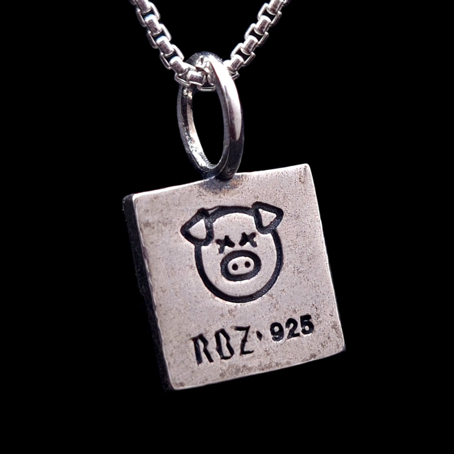Reverse side of the sterling silver ACAB pendant featuring an engraved X-eyed pig graphic and the RBZ 925 hallmark on a brushed brutalist metal finish.