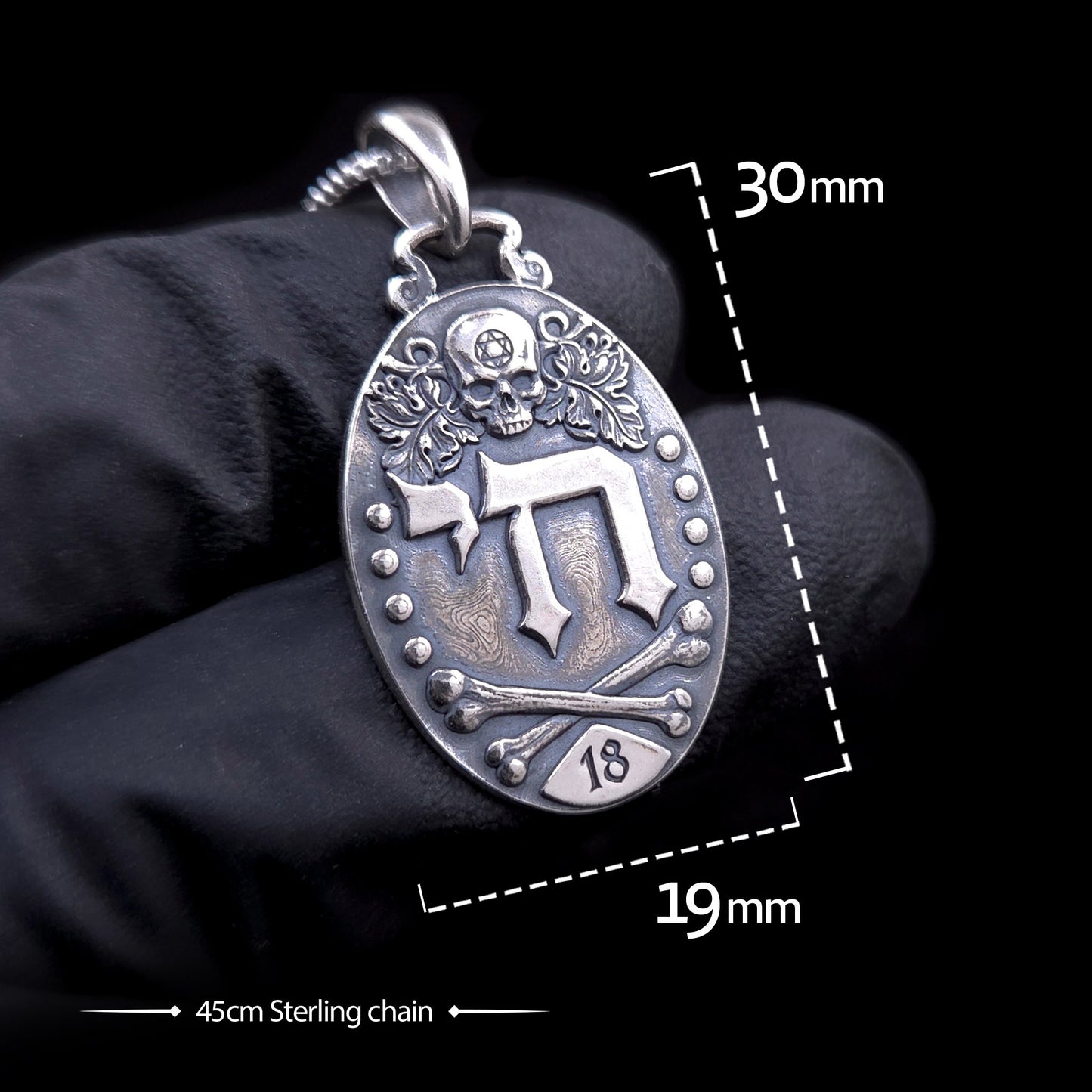 Gothic Judaica sterling silver Chai pendant by RBZ, held in a black-gloved hand for scale, featuring dimension overlays of 30mm height by 19mm width and a 45cm sterling silver chain.
