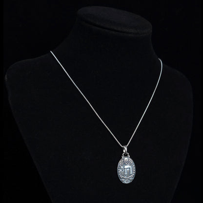 Gothic Judaica sterling silver Chai pendant by RBZ Jewelry, displayed on a silver chain around a black mannequin display bust to show necklace drop length.