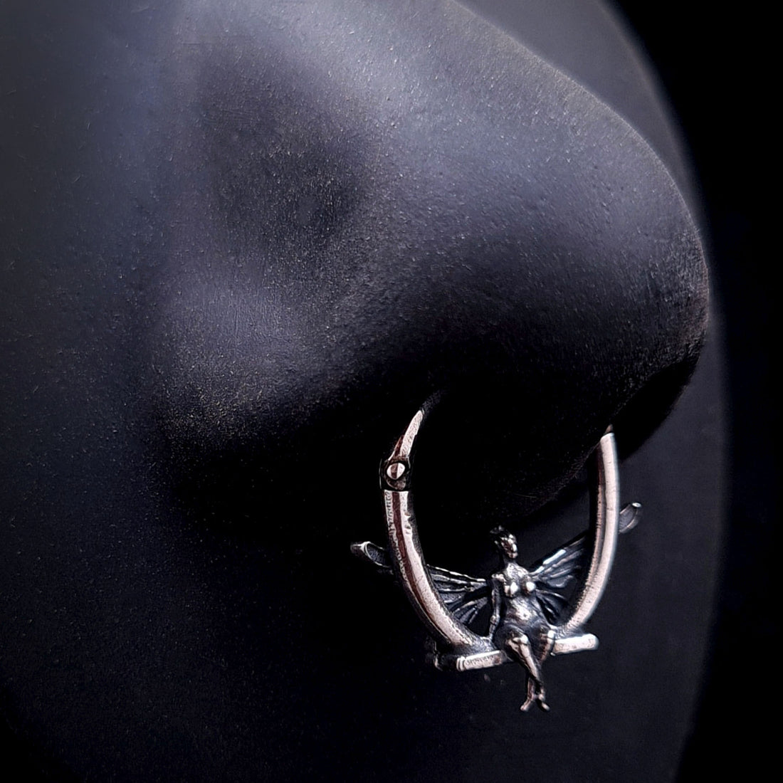 Solid 925 sterling silver fairy septum clicker worn on a realistic black silicone nose mannequin to demonstrate scale, fit, and visual placement.