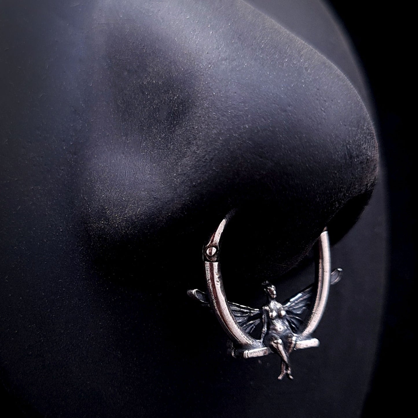 Solid 925 sterling silver fairy septum clicker worn on a realistic black silicone nose mannequin to demonstrate scale, fit, and visual placement.