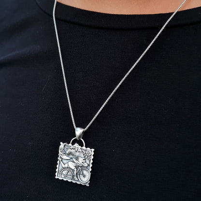 A person wearing the sterling silver Bicycle Day necklace, a unique piece of wearable counter-culture art