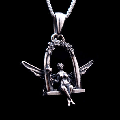 Sterling silver Flower Fairy pendant by RBZ Jewelry, featuring an intricately detailed fairy with spread wings sitting on a floral-arched swing and holding a star-tipped wand against a black background.