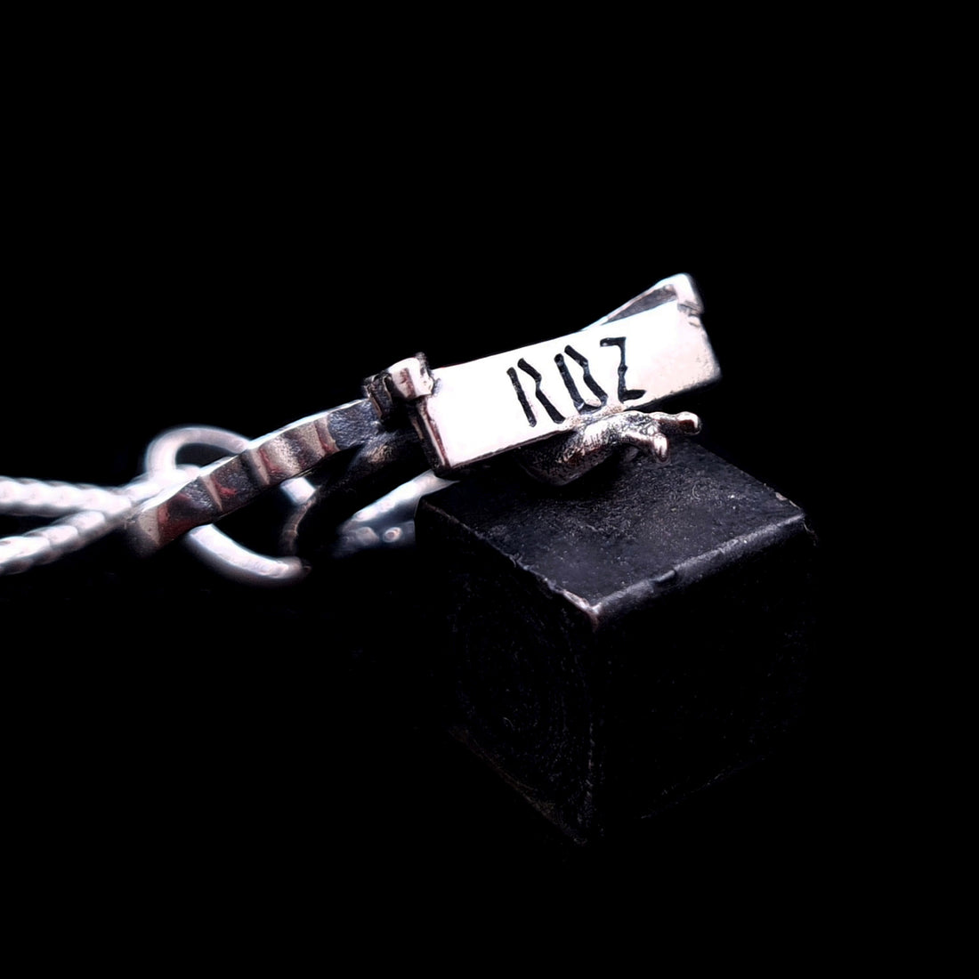 Bottom view of the sterling silver Flower Fairy pendant by RBZ Jewelry, showcasing the engraved RBZ brand logo on the base of the swing seat.