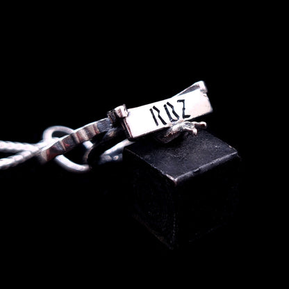 Bottom view of the sterling silver Flower Fairy pendant by RBZ Jewelry, showcasing the engraved RBZ brand logo on the base of the swing seat.