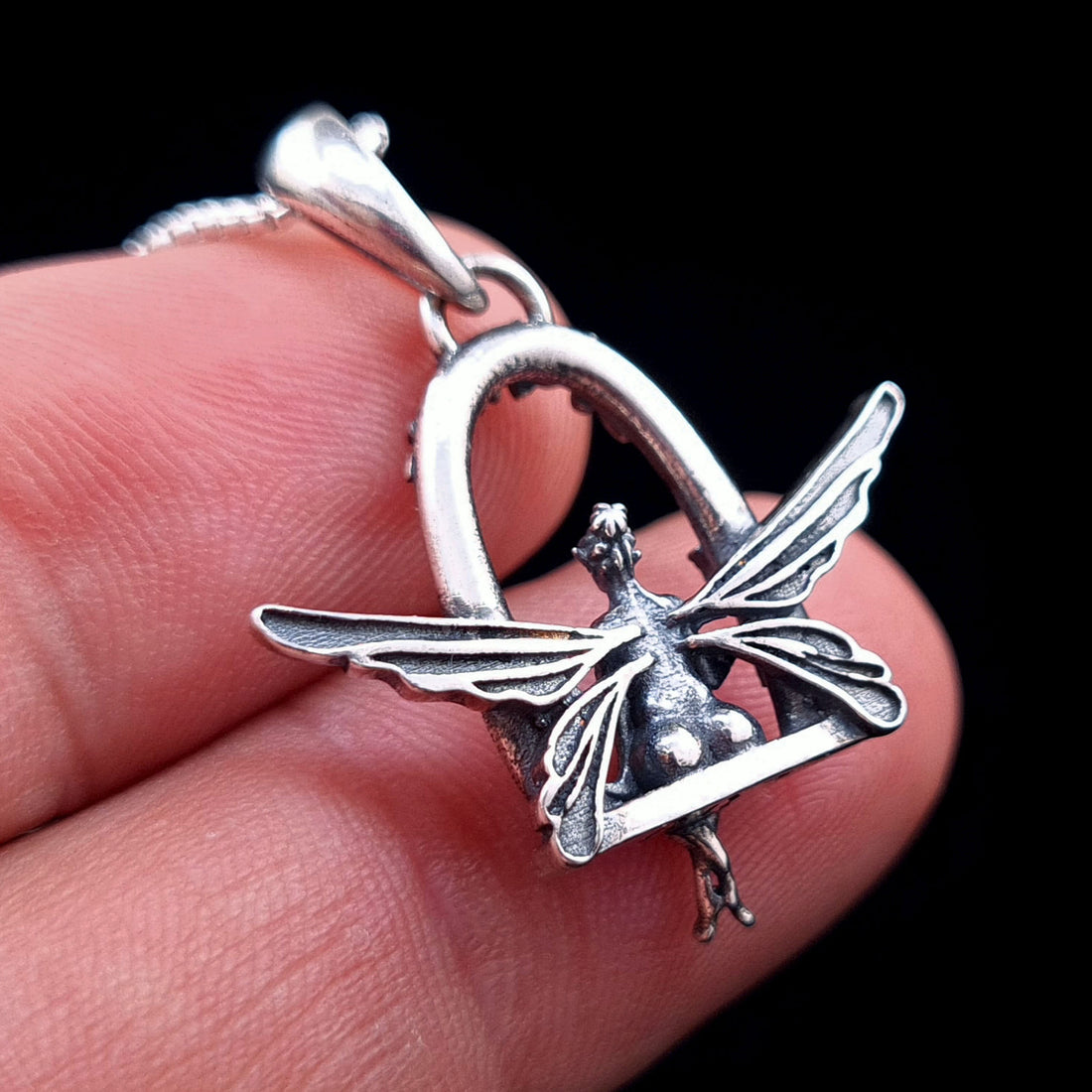 Back view of the sterling silver Flower Fairy pendant by RBZ Jewelry held in hand, showing the intricate details of the fairy’s wings and the reverse side of the floral swing seat.