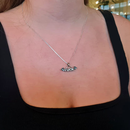 A female model wearing the sterling silver Flying Fuck pendant by RBZ Jewelry on a silver chain, styled with a black square-neck top to demonstrate the necklace length and scale.