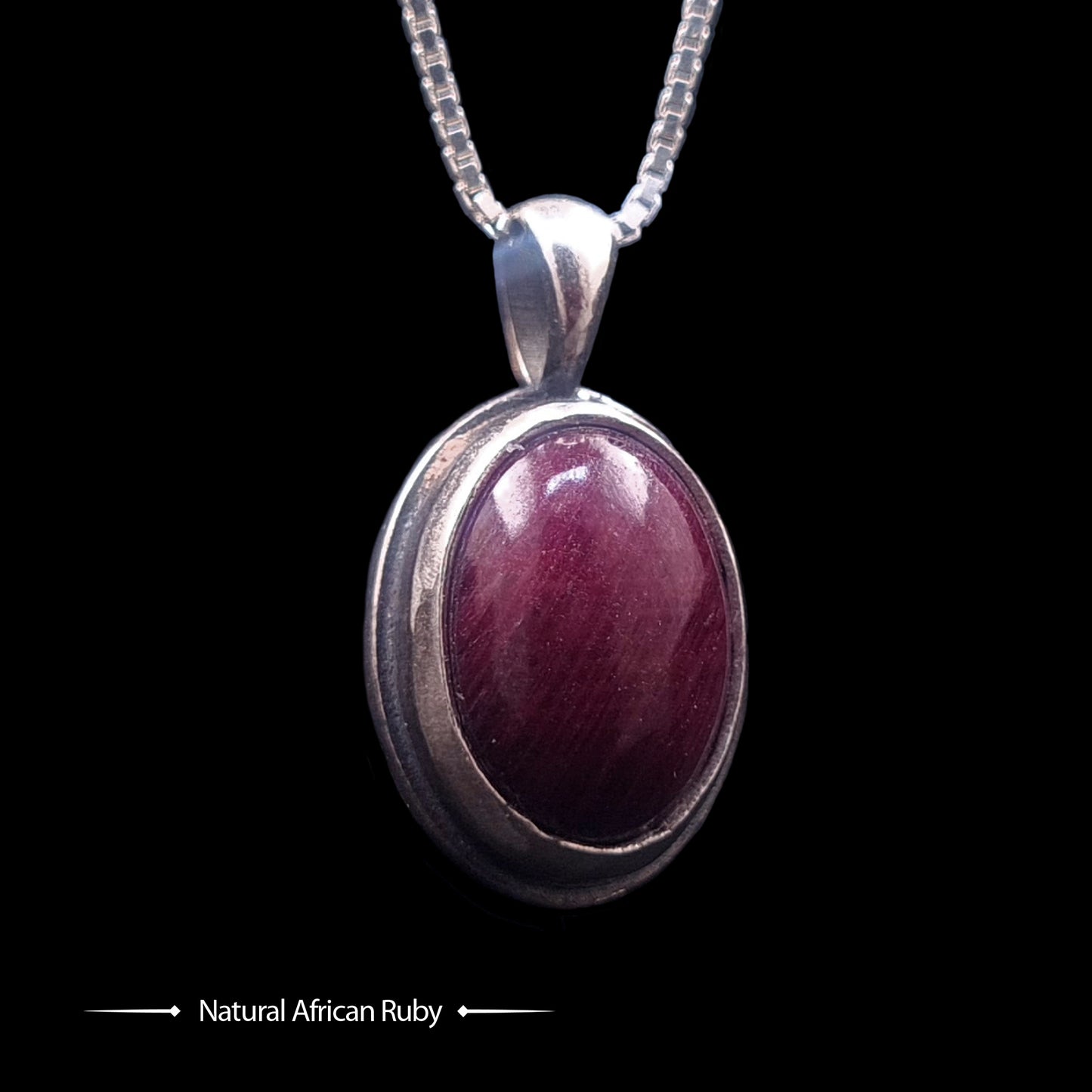 Studio-crafted RBZ Jewelry Gothic pendant featuring a deep purple-red Natural African Ruby cabochon encased in a polished Sterling silver bezel, front view of the double-sided Skull Bezel design on a silver box chain.