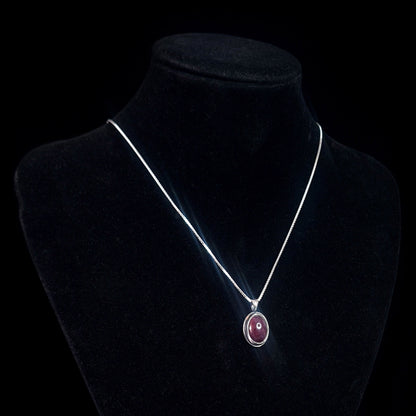 Studio-crafted RBZ Jewelry Gothic Sterling silver pendant featuring a Natural African Ruby cabochon, displayed on a black velvet necklace bust to show how the pendant hangs from its silver chain.