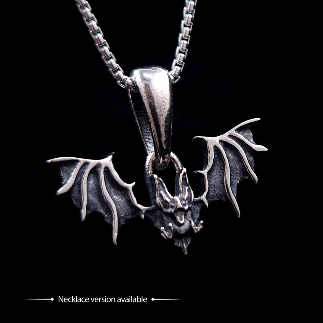 Gothic Sterling silver Glitched Bat pendant necklace by RBZ Jewelry, featuring a visceral, distorted bat silhouette with textured spread wings on a silver box chain. The image includes text at the bottom stating "Necklace version available," set against a solid black background.