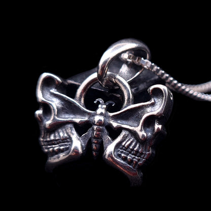 RBZ Jewelry Sterling silver Gothic Butterfly Skull pendant featuring detailed wings sculpted into human skull profiles, displayed on a silver chain against a black background.