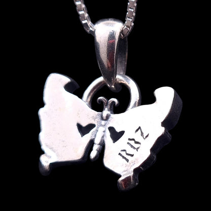 The back side of the Sterling silver Gothic Butterfly Skull pendant by RBZ Jewelry, featuring the RBZ logo engraving, two heart-shaped cutouts, and a polished finish against a black background.
