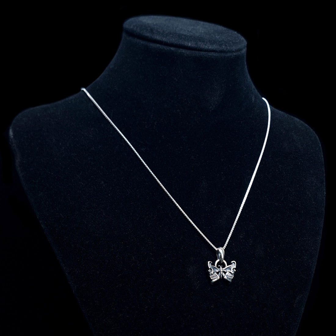RBZ Jewelry Sterling silver Gothic Butterfly Skull pendant on a long silver chain, displayed on a black velvet mannequin bust against a black background to show scale and wear.