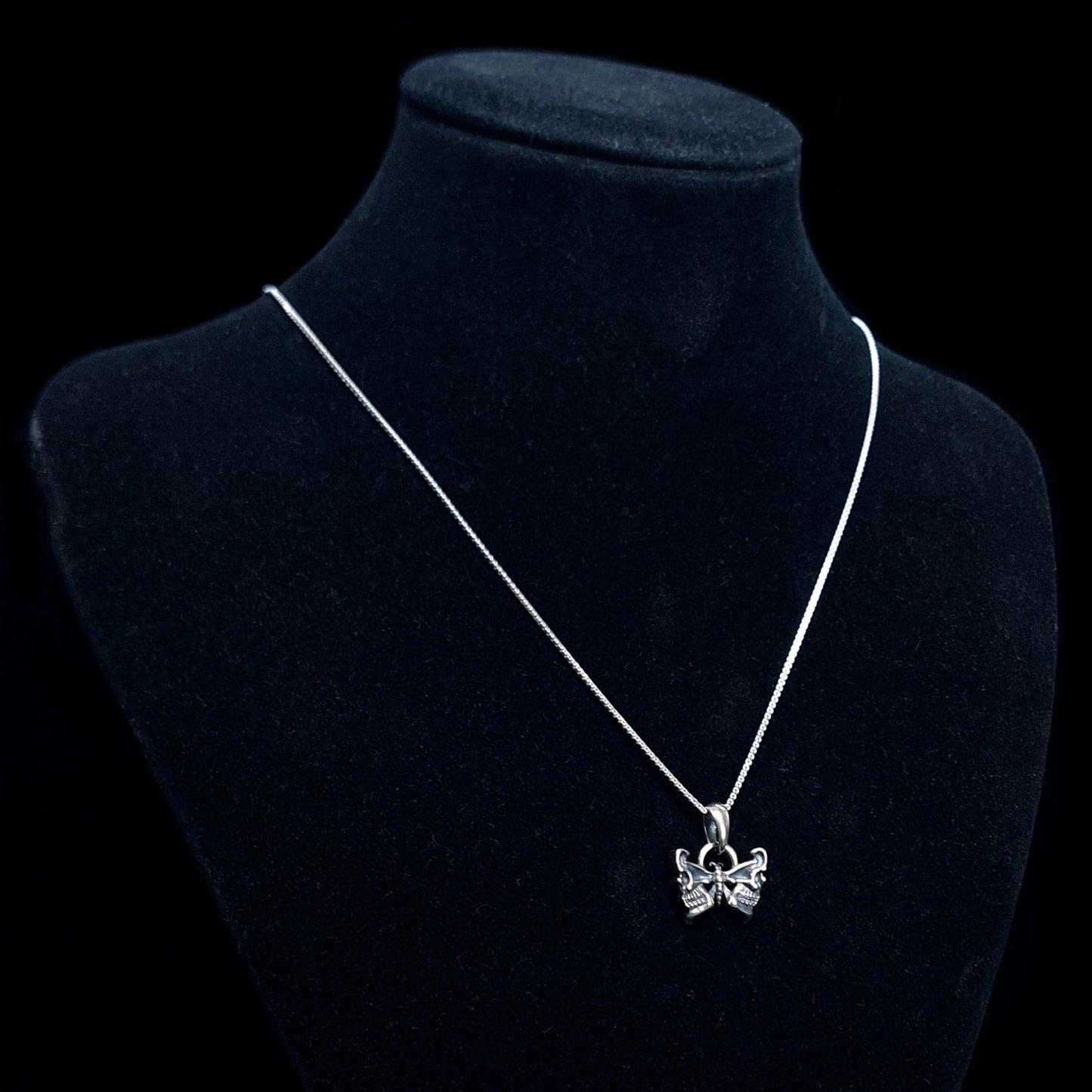 RBZ Jewelry Sterling silver Gothic Butterfly Skull pendant on a long silver chain, displayed on a black velvet mannequin bust against a black background to show scale and wear.