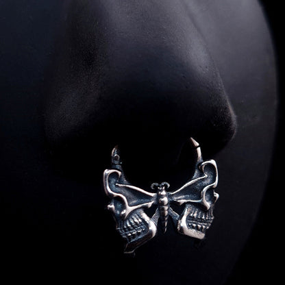 Sterling silver Gothic butterfly skull septum clicker ring by RBZ Jewelry, shown as worn on a life-size black silicone nose model to demonstrate its appearance and scale.