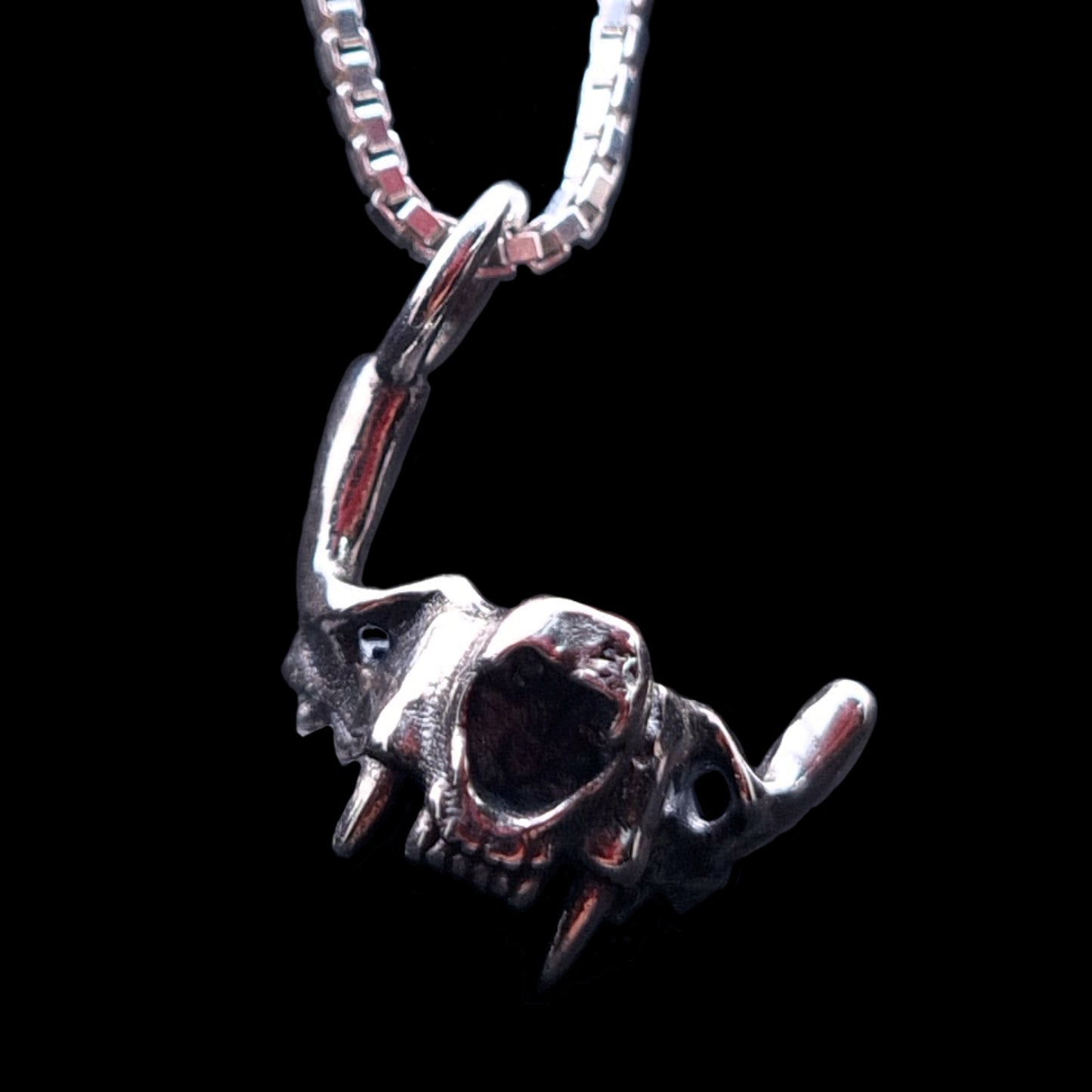 Frontal view of the RBZ Jewelry Sterling silver Gothic Cat Skull Jawbone pendant, highlighting the anatomical feline fangs and macabre skeletal detail on a silver chain against a black background.