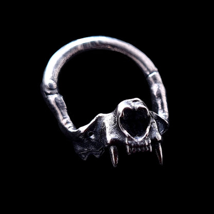 Detailed front view of the RBZ Jewelry sterling silver cat skull septum ring, featuring realistic anatomical bone texture, prominent fangs, and a gothic clicker design against a black background.