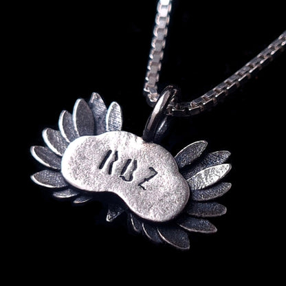 Back view of the sterling silver Moon Owl pendant by RBZ Jewelry, showcasing the "RBZ" maker's mark engraved on the smooth reverse surface framed by detailed oxidized wings, hanging on a silver box chain against a black background.