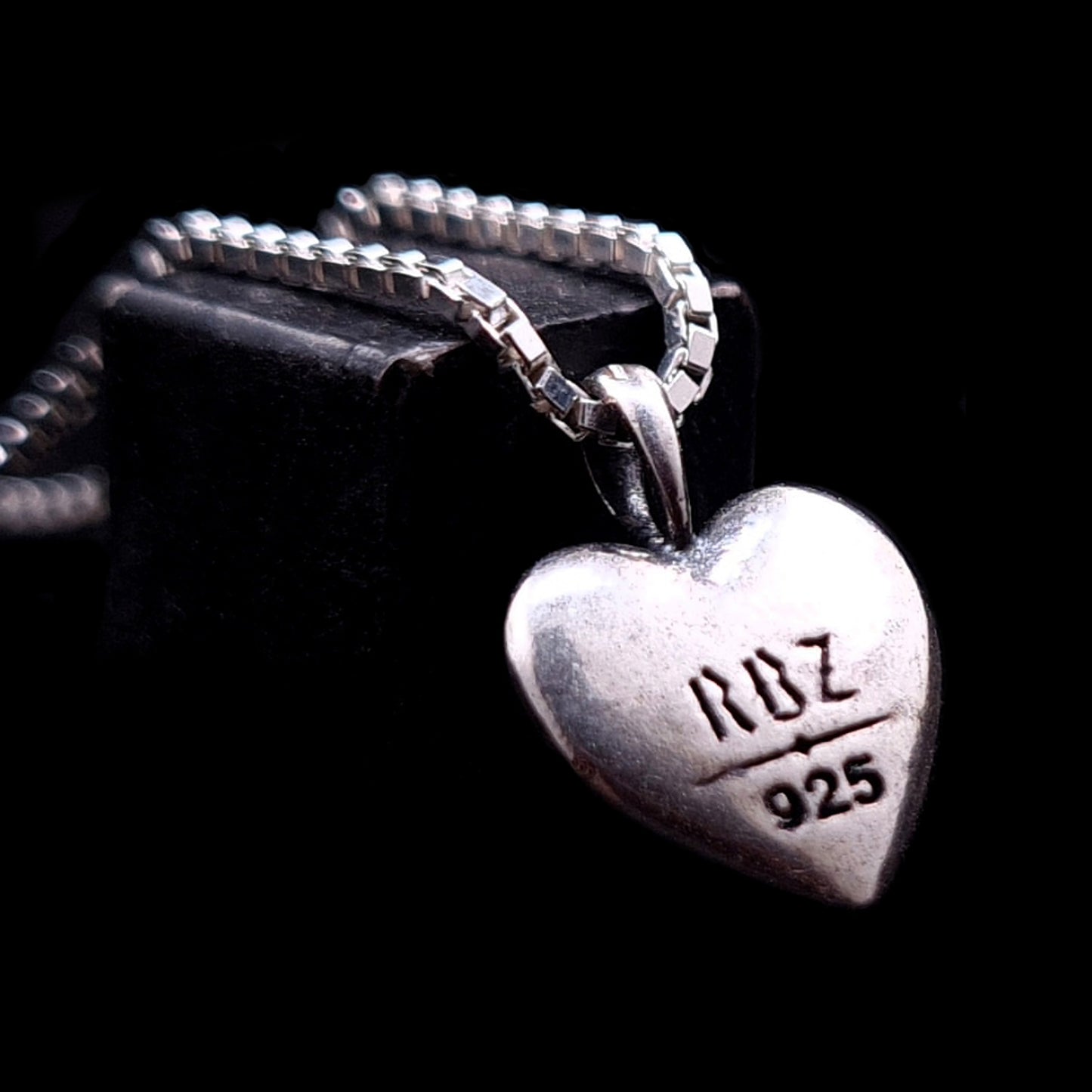The back side of the RBZ Jewelry Gothic Ribcage Heart pendant in sterling silver, featuring an engraved RBZ logo and 925 hallmark on a polished surface.