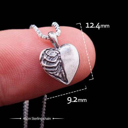 Sterling silver Gothic Ribcage Heart pendant by RBZ Jewelry held on a finger for scale, with overlay text indicating dimensions of 12.4mm by 9.2mm and a 45cm sterling silver chain.