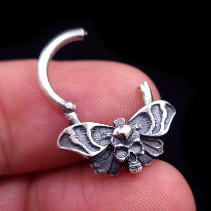 Sterling silver Gothic Death Moth septum ring shown in the open position, held between fingers to demonstrate the hinged clicker mechanism and the scale of the intricate skull and wing details, made by RBZ Jewelry.