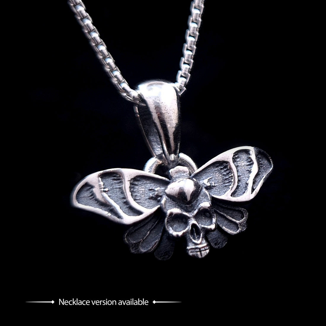 Sterling silver Gothic Death Moth pendant necklace, by RBZ Jewelry, featuring an intricate skull motif on the thorax and detailed spread wings, suspended from a silver chain against a black background.