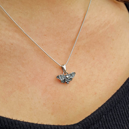 Lifestyle shot of the Gothic Death Moth pendant worn on a sterling silver chain around the neck by RBZ Jewelry.