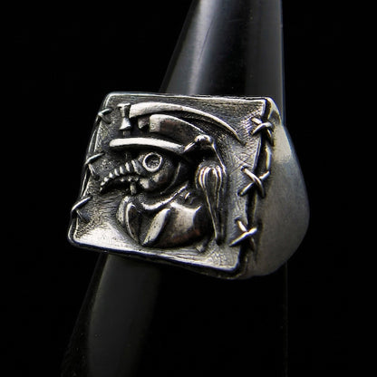 Sterling silver Plague Doctor signet ring by RBZ Jewelry featuring a high-relief sculpture of a beaked mask, raven, and sickle with hand-stitched border detailing.