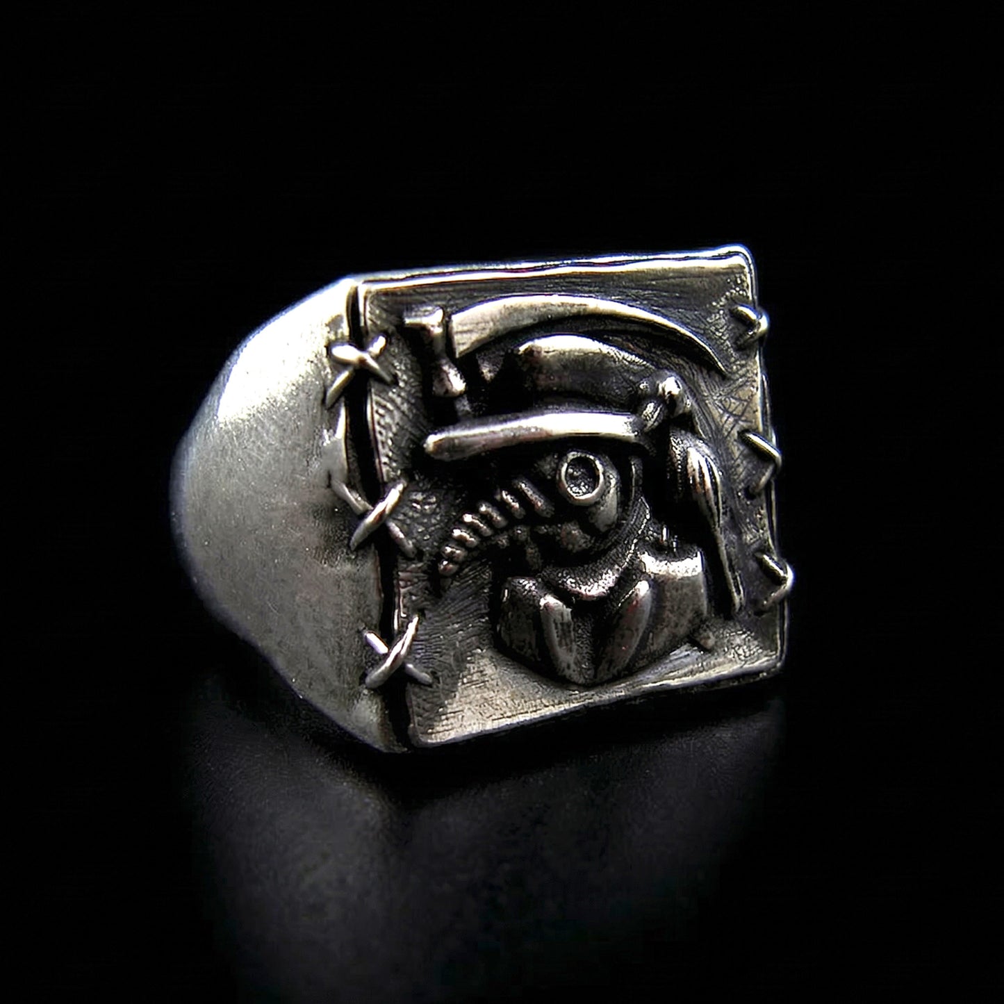 Angled right-facing view of the Sterling silver Plague Doctor signet ring by RBZ Jewelry, featuring high-relief carvings of the beaked mask, raven, and sickle with a stitched border.