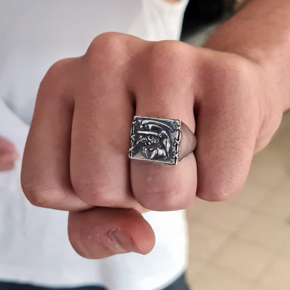 Sterling silver Plague Doctor signet ring by RBZ Jewelry worn on a male model's clenched fist, displaying the detailed high-relief carving of the beaked mask, raven, and sickle.