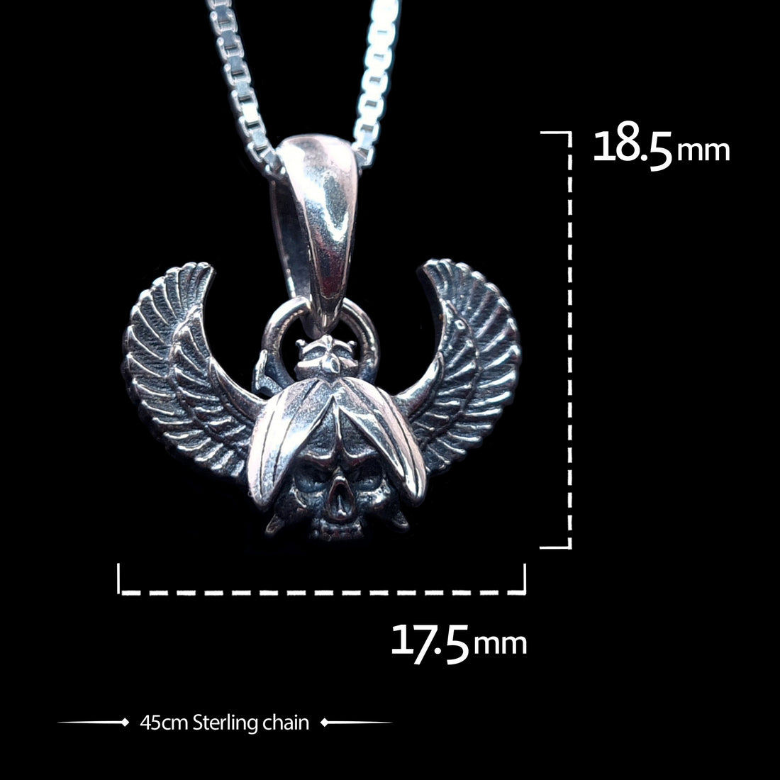 Front view of the sterling silver Gothic Egyptian Skull Scarab pendant by RBZ Jewelry, displaying dimensions of 18.5mm in height and 17.5mm in width. The pendant, featuring a detailed skull centered within outstretched feathered wings, is shown on a 45cm sterling silver chain against a black background.
