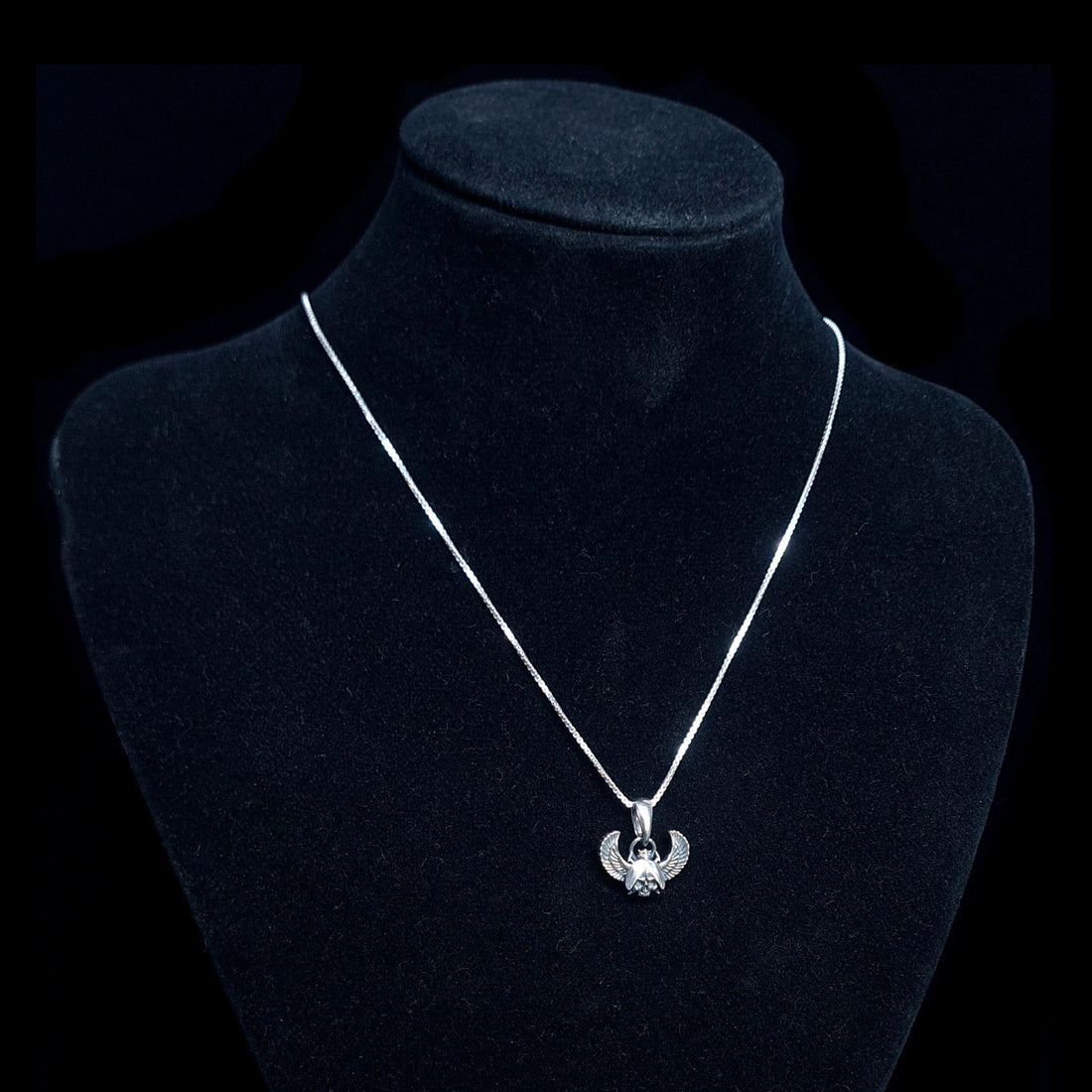 Sterling silver Gothic Egyptian Skull Scarab pendant by RBZ Jewelry, displayed on a black velvet mannequin bust to show the pendant's scale and how it hangs on a silver chain.