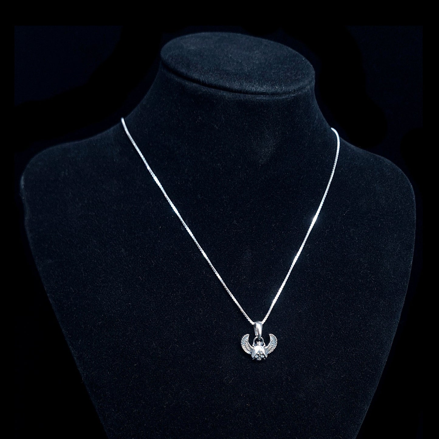 Sterling silver Gothic Egyptian Skull Scarab pendant by RBZ Jewelry, displayed on a black velvet mannequin bust to show the pendant's scale and how it hangs on a silver chain.