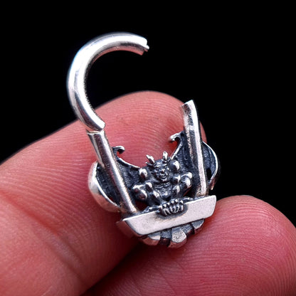 A close-up of the RBZ Jewelry Gargoyle Guardian septum ring held between fingers, showing the sterling silver clicker in its open position to demonstrate the hinge mechanism and provide a sense of scale for the intricate gothic gargoyle design.
