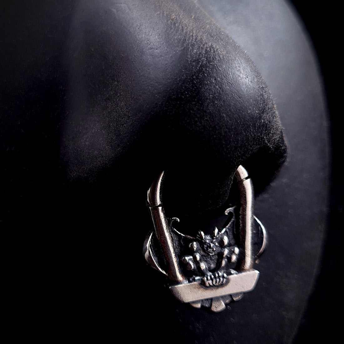 The RBZ Jewelry Gargoyle Guardian septum ring displayed on a life-size black silicone nose model, demonstrating the scale and visual impact of the detailed sterling silver gothic gargoyle design when worn in a septum piercing.