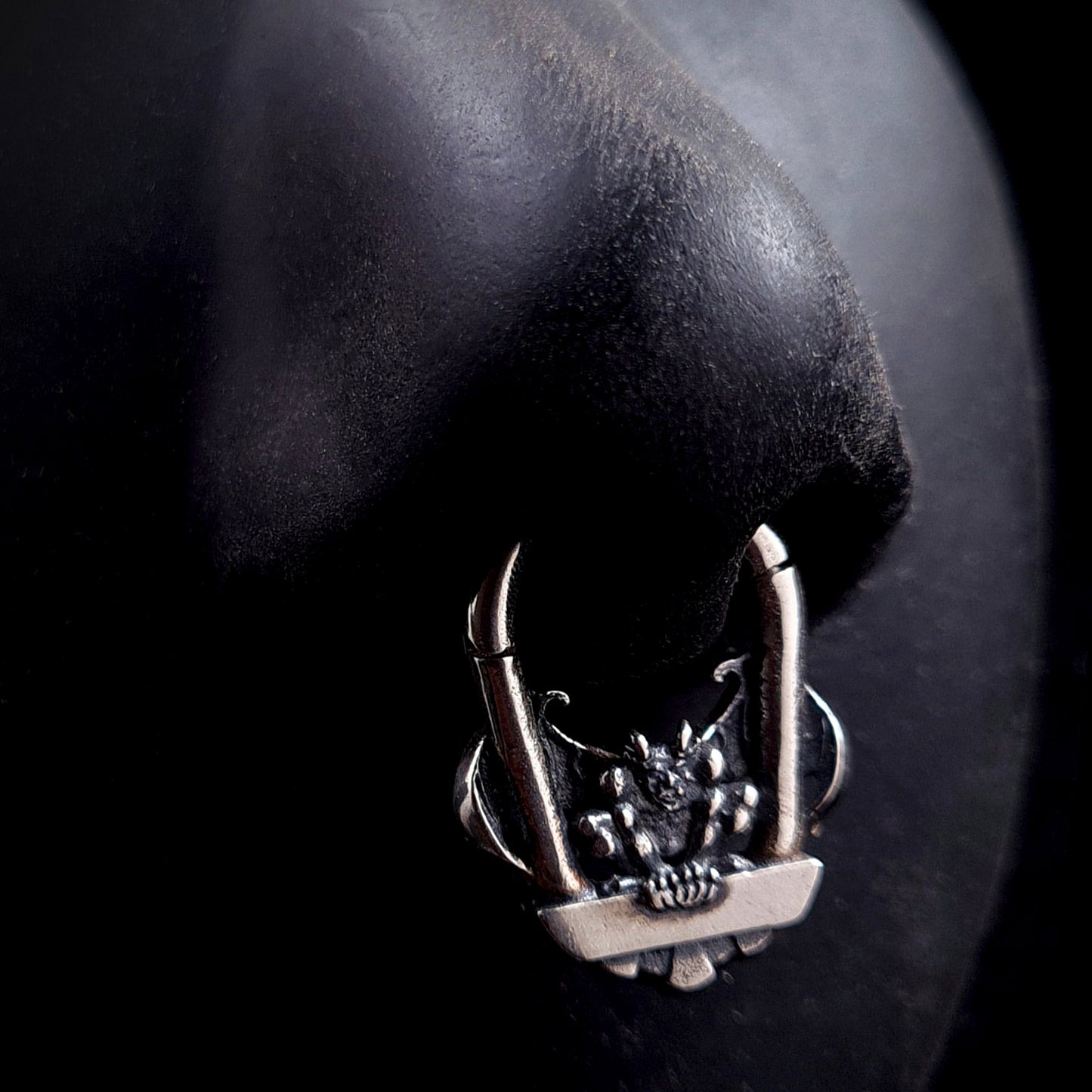 The RBZ Jewelry Gargoyle Guardian septum ring displayed on a life-size black silicone nose model, demonstrating the scale and visual impact of the detailed sterling silver gothic gargoyle design when worn in a septum piercing.
