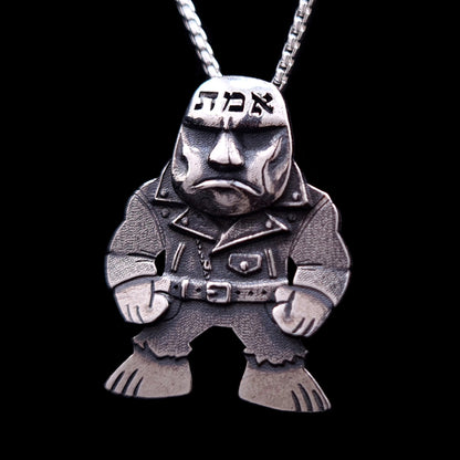 Handcrafted sterling silver Golem of Prague pendant by RBZ Jewelry, featuring a gritty punk-rock reimagining of the legendary clay giant wearing a weathered leather jacket and belt with clenched fists. The gothic-style figure includes the Hebrew word אמת (Truth) deeply engraved on its forehead, suspended from a silver chain against a black background.