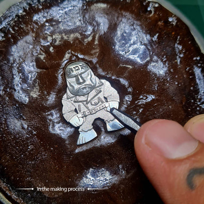 Handcrafted sterling silver Golem of Prague pendant by RBZ Jewelry, shown secured in an engraver's substance, highlighting the artisanal touch of the artist.