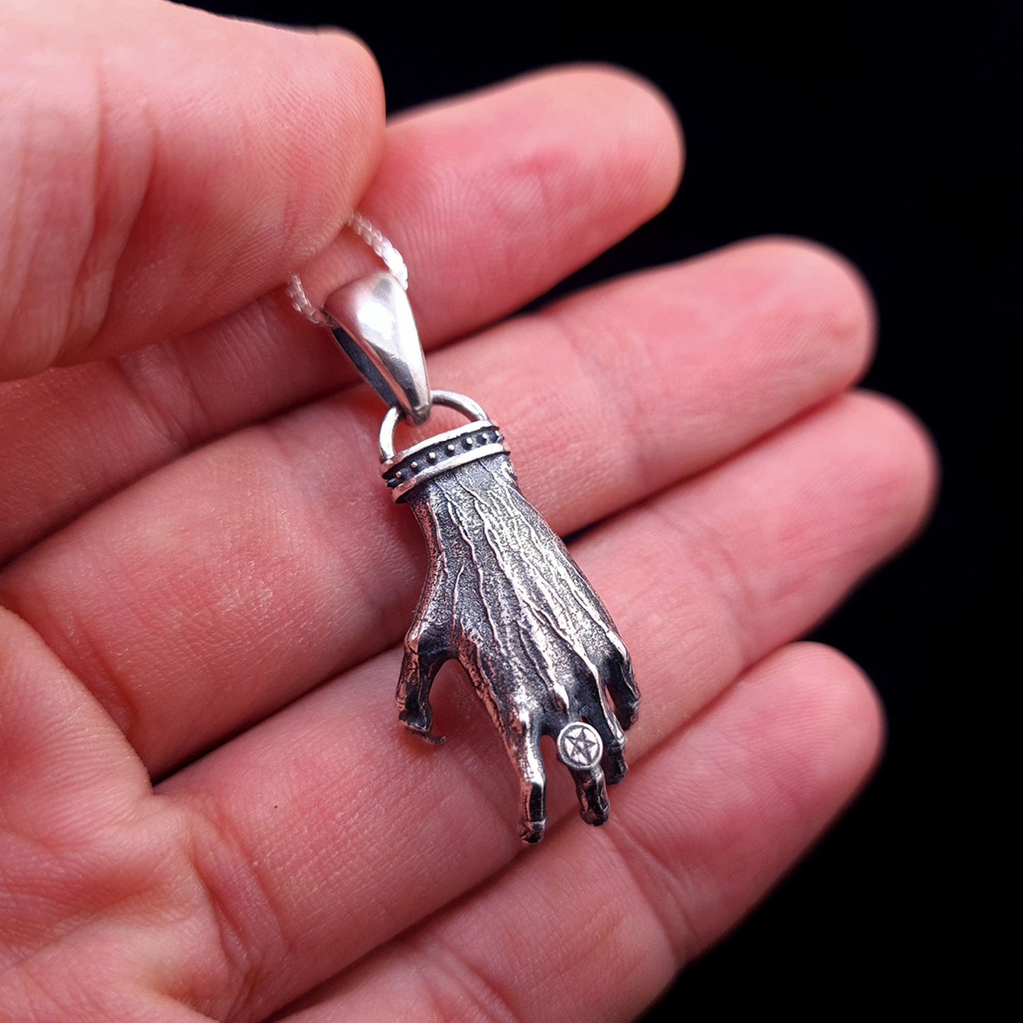 'The Nocturnal Hamsa' Sterling Silver Pendant by RBZ Jewelry - Rear perspective held in hand for scale, featuring the detailed texture of the gothic clawed hand and the intricate pentagram ring detail with an oxidized finish.