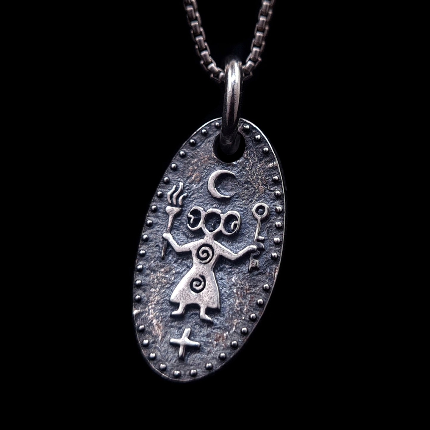 Front view of the Hecate, Greek triple goddess medallion in solid 925 sterling silver by RBZ Jewelry, featuring an oxidized ancient cave art style with torches, key, and crescent moon symbols