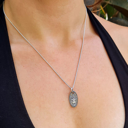Lifestyle photo of the Hecate triple goddess pendant by RBZ Jewelry worn by a model on a solid 925 sterling silver box chain, demonstrating the pendant's scale and how it hangs as a delicate everyday talisman
