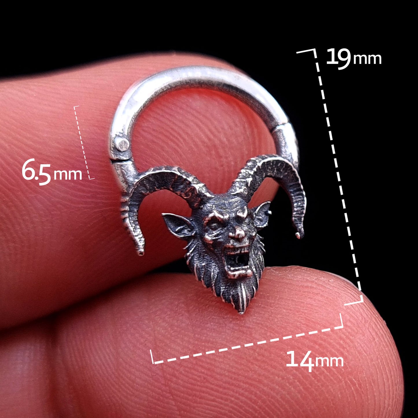 Front view of the sterling silver Horned Demon septum clicker ring by RBZ Jewelry held between fingers, featuring overlaid measurement graphics indicating a 19mm total height, 14mm overall width, and a 6.5mm inner wearable drop, set against a black background.