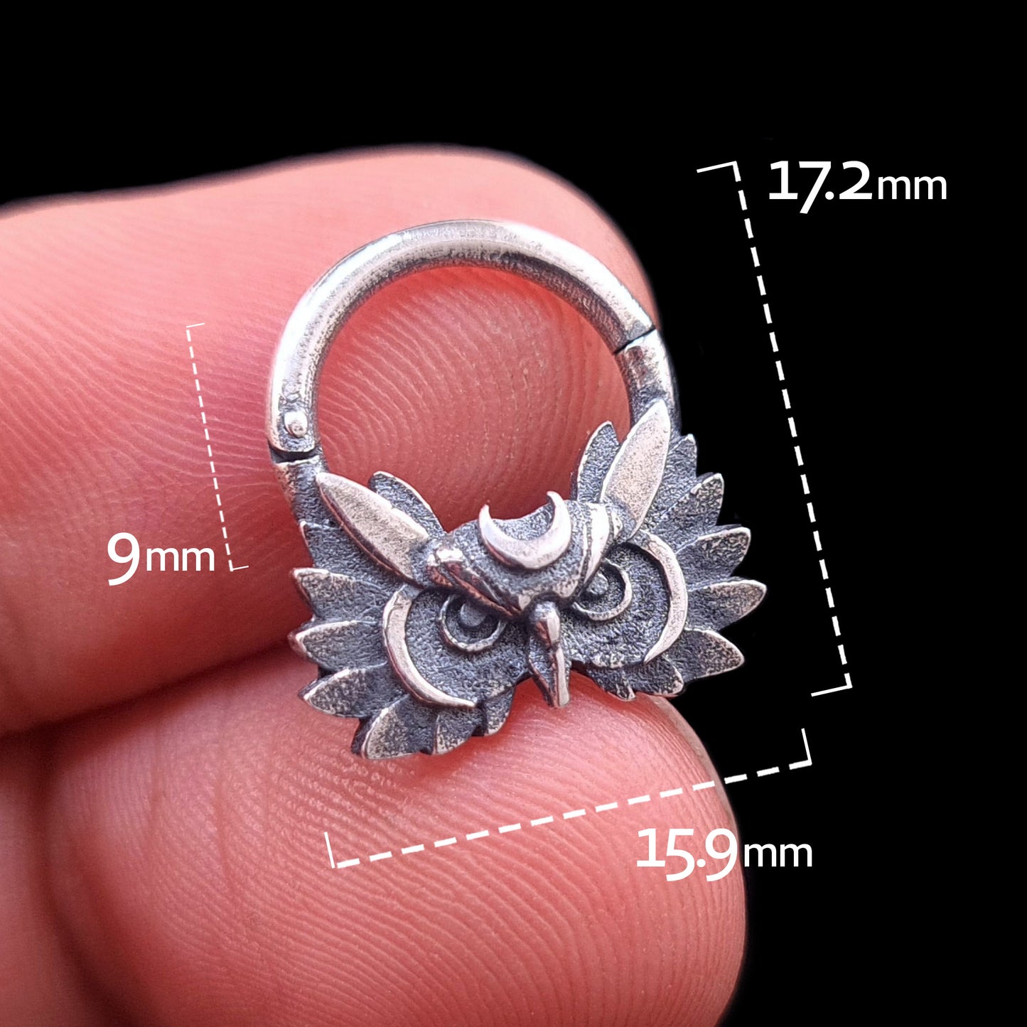 Handheld front view of the Sterling silver Moon Owl septum ring by RBZ Jewelry, showcasing the intricate owl design and crescent moon crown. The image includes scale markers indicating dimensions of 9mm inner drop, 15.9mm width, and 17.2mm total height, held against a black background.
