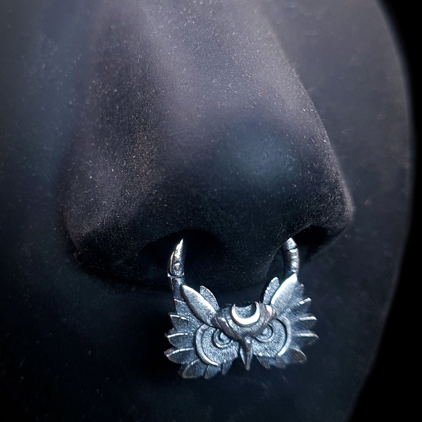 Sterling silver Moon Owl septum ring by RBZ Jewelry, shown worn on a life-size black silicone nose mannequin to demonstrate placement and scale. The handcrafted, gothic-style septum clicker features a detailed owl face and crescent moon with a dark oxidized finish.