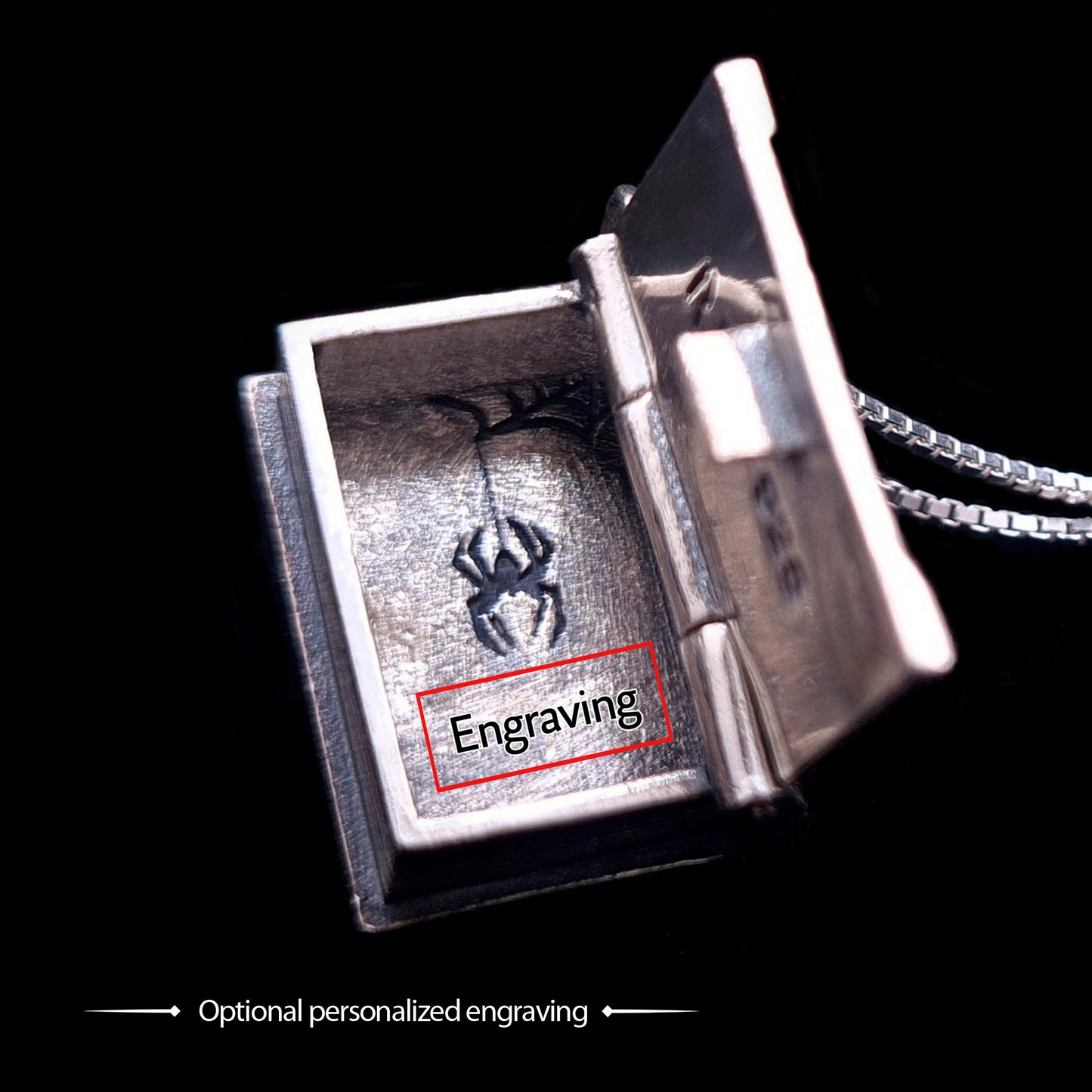 Open view of the sterling silver Necronomicon book locket pendant, highlighting the customization options. The hollow interior features the secret spider engraving and a red box labeled "Engraving" to indicate the location for optional personalized text. The image showcases the polished silver walls, the functional hinge, and the silver box chain against a black background, emphasizing the high-quality nature of this RBZ Jewelry gothic horror piece.