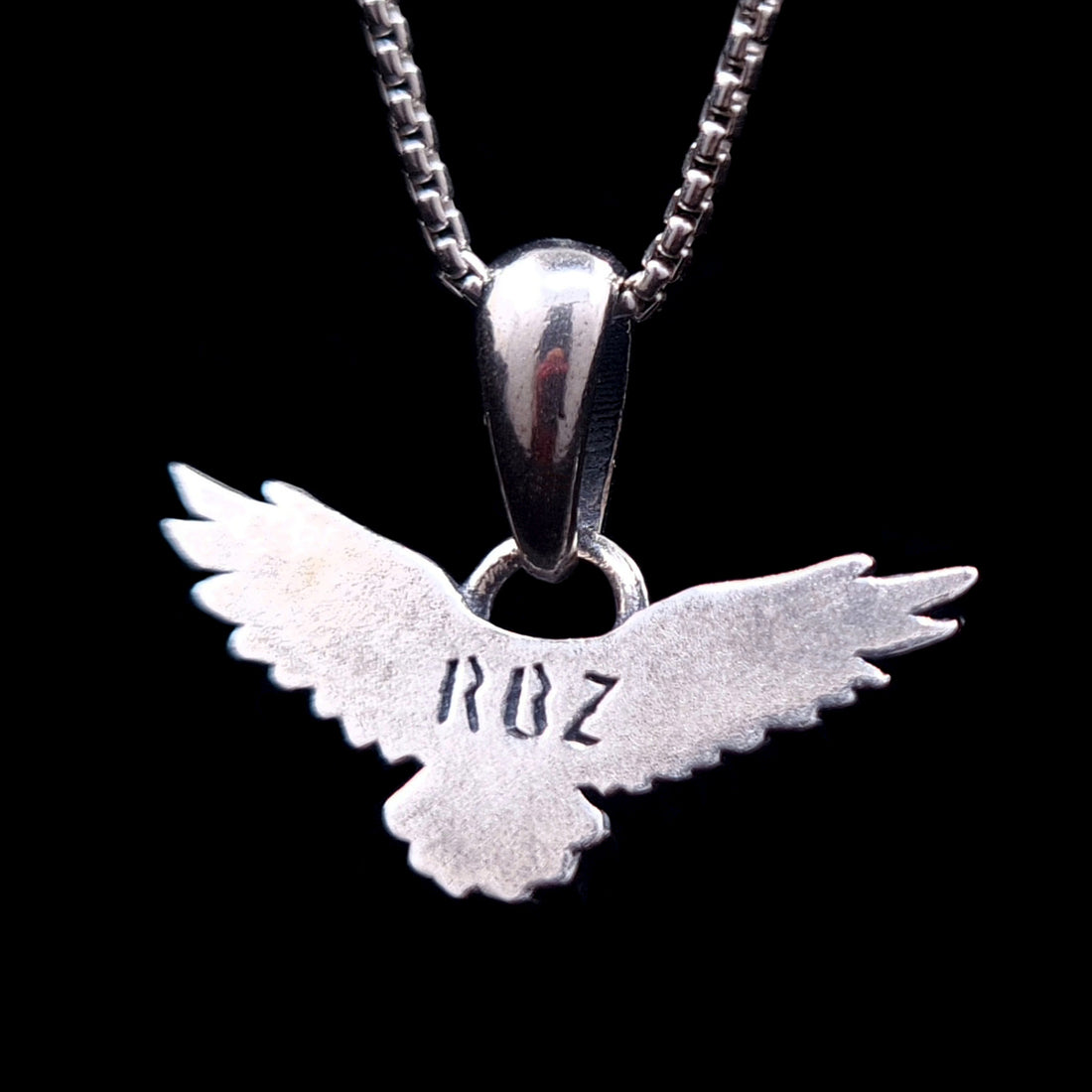 Back view of the sterling silver flying raven pendant featuring the RBZ brand engraving on the smooth reverse side, handcrafted Gothic crow necklace by RBZ Jewelry.